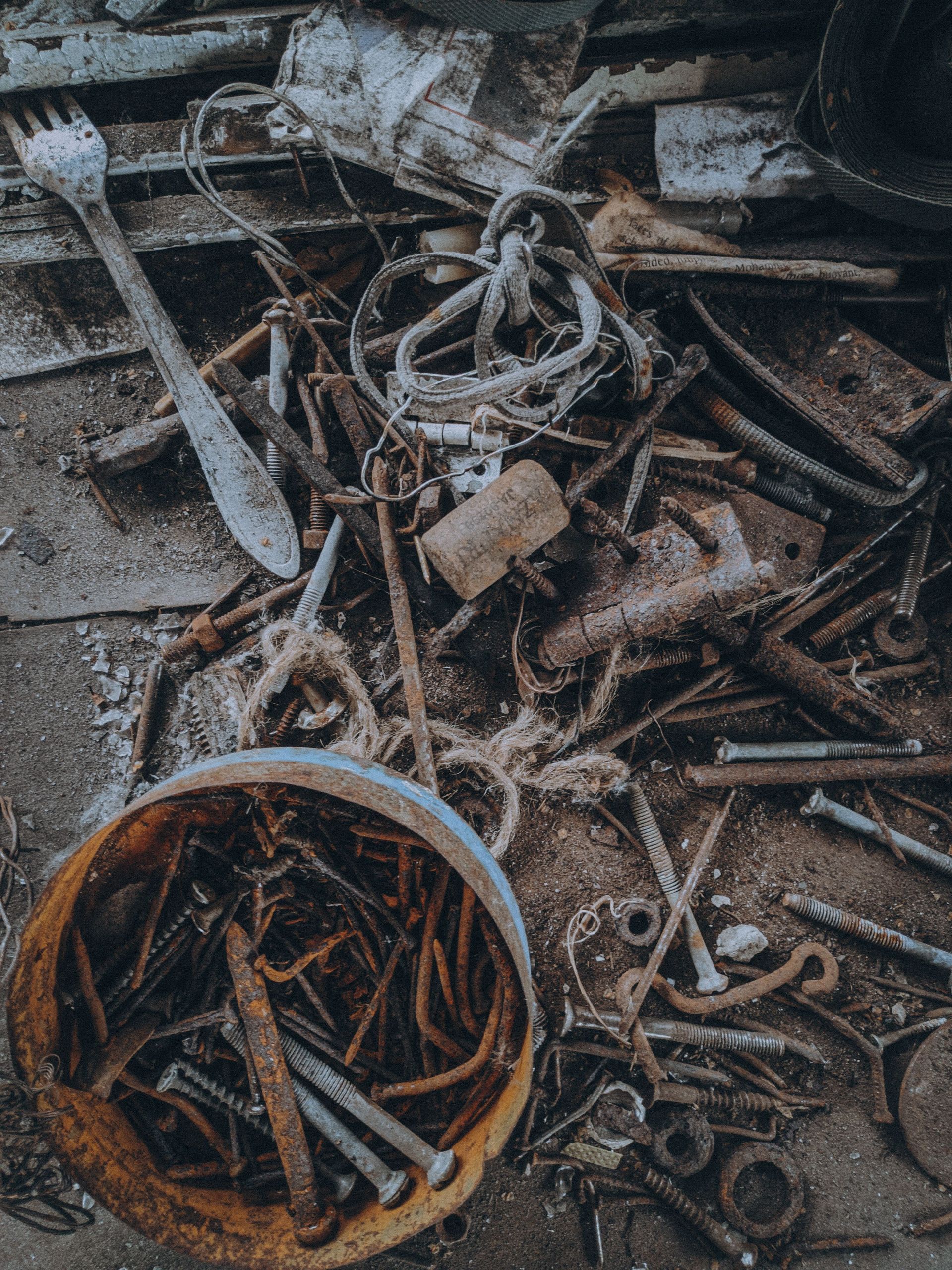 A detailed view of assorted rusty metal scraps and tools on the ground, conveying industrial decay.